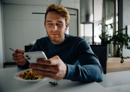 Man in Plaid Shirt Using Smartphone